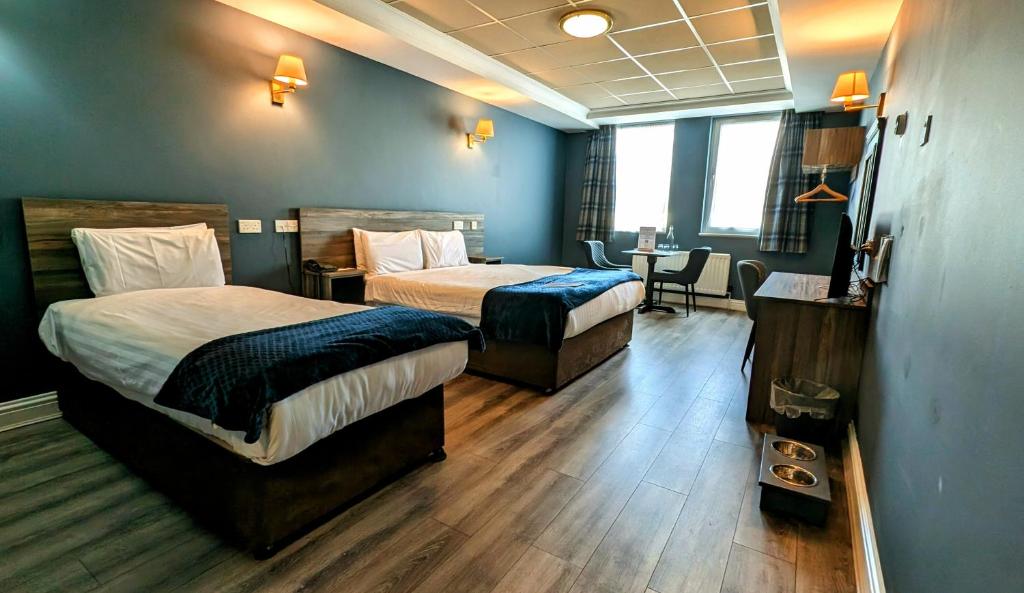 a hotel room with two beds and a table at Inn On The Coast in Portrush