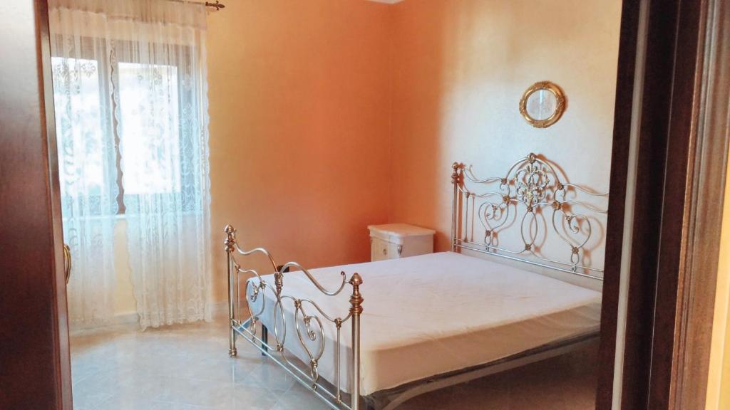 ein Schlafzimmer mit einem weißen Bett in einem orangefarbenen Zimmer in der Unterkunft One bedroom apartement with furnished balcony and wifi at Montagnareale 5 km away from the beach in Montagnareale