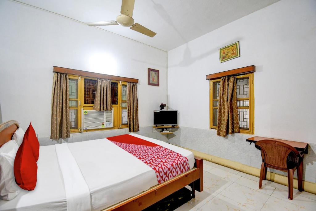 a bedroom with a large bed and two windows at Hotel Upasana in Bhubaneshwar