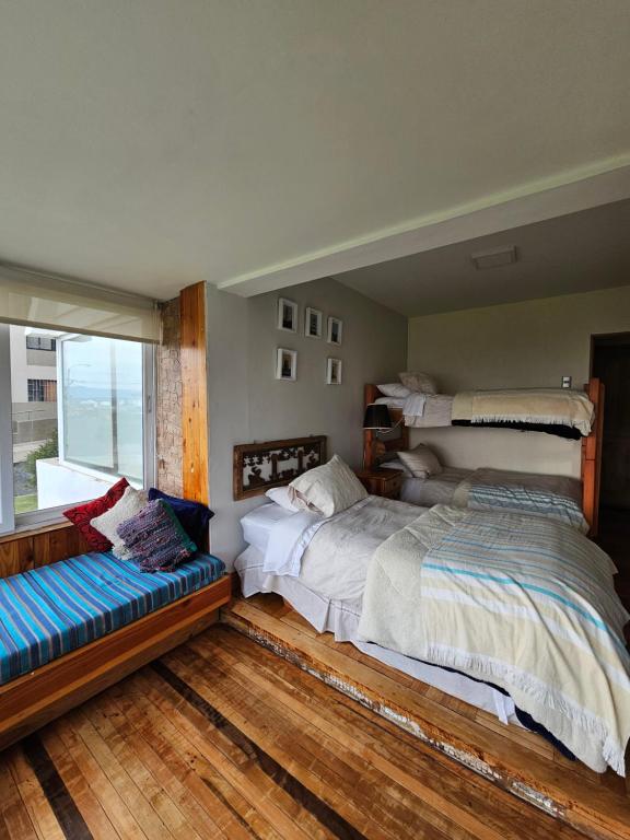 1 dormitorio con 2 camas, banco y ventana en Departamento Frente al Mar en Viña del Mar