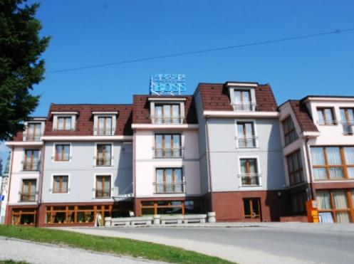 a large white building with a sign on top of it at Hotel Boss in Žilina