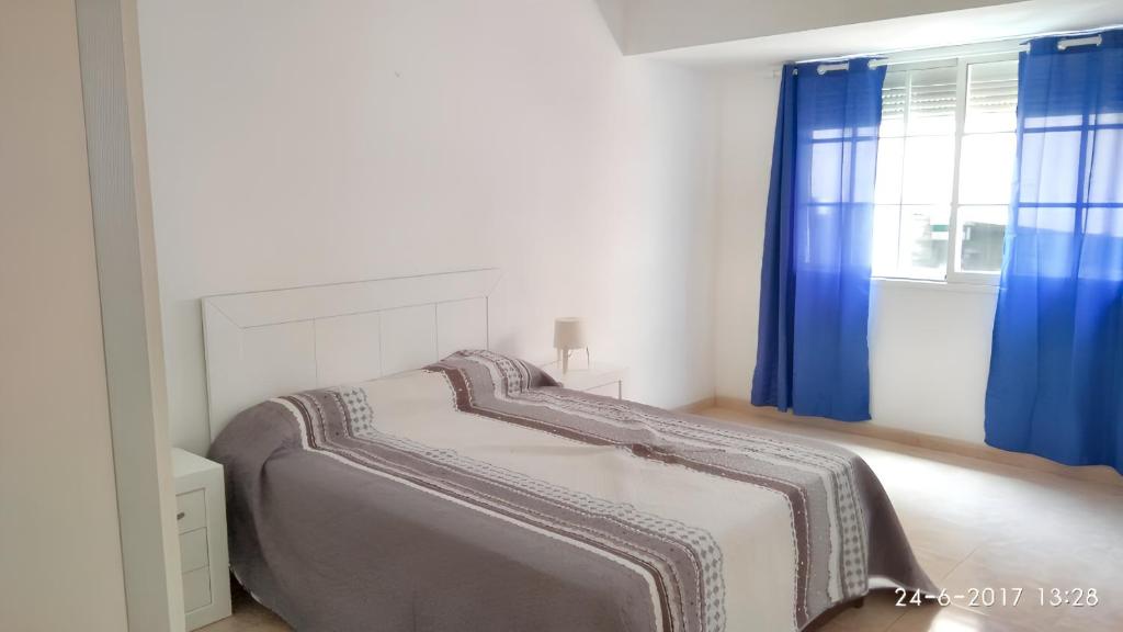 um quarto com uma cama e uma janela com cortinas azuis em 3 bedrooms apartement at Arrecife 800 m away from the beach with balcony and wifi em Arrecife