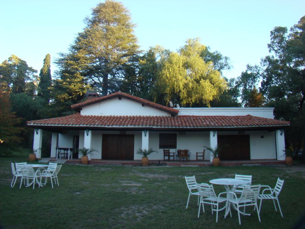 a white house with tables and chairs in the yard at Cabañas La Victoria, Las Calles, Traslasierras, Córdoba in Las Rabonas