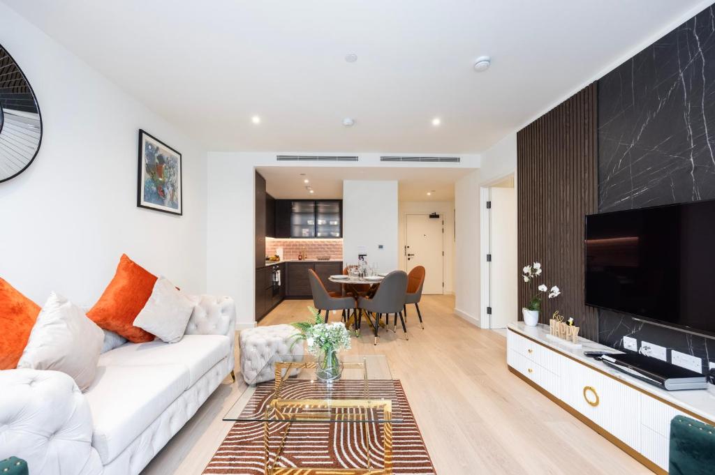 een woonkamer met een witte bank en een tafel bij Austin David Apartments Royal Wharf in Londen