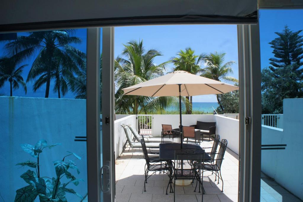 patio ze stołem, krzesłami i parasolem w obiekcie Beachfront Townhouse with private patio, direct beach access, gym, bars & free parking! w Miami Beach