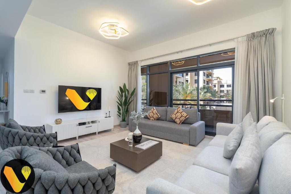 ein Wohnzimmer mit 2 Sofas und einem TV in der Unterkunft Vogue - The Greens and Views in Dubai
