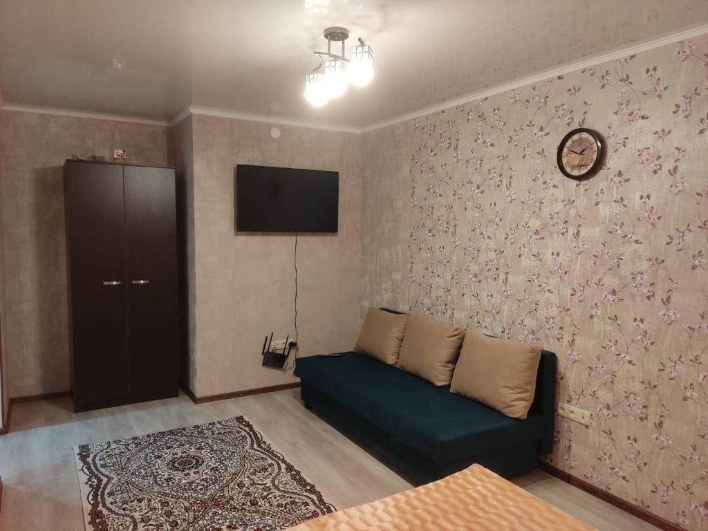 a living room with a couch and a tv on a wall at 1-комнатная квартира in Balqash