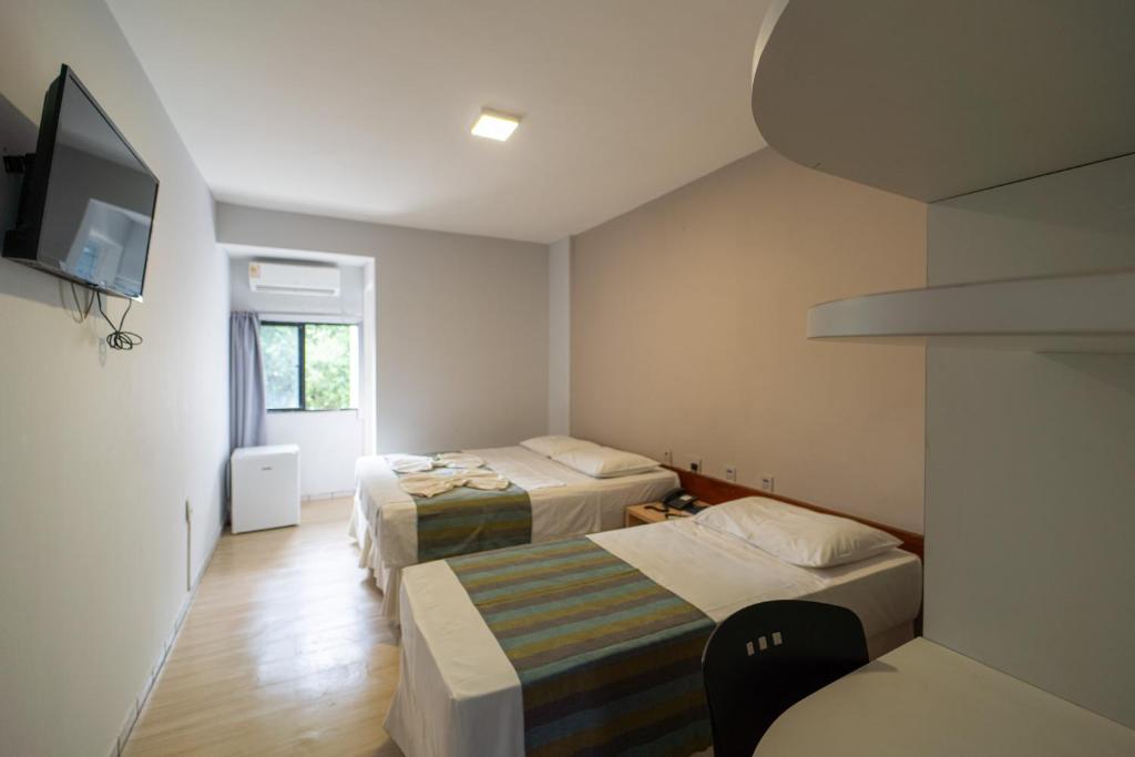 ジョアンペソアにあるLagoa Park Hotelのベッド2台とテレビが備わる小さな客室です。