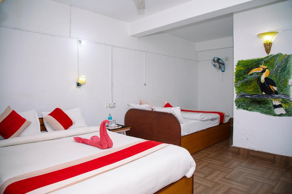 a bedroom with two beds and a bird painting on the wall at Hotel Shiva's Dream in Sauraha