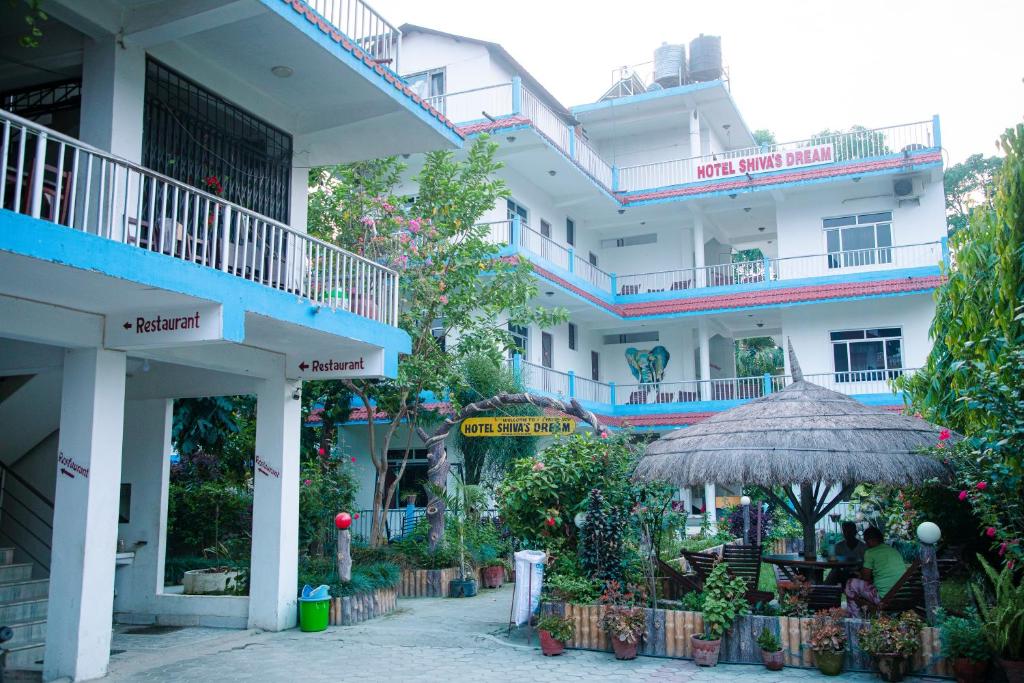 a building with balconies and tables and an umbrella at Hotel Shiva's Dream in Sauraha