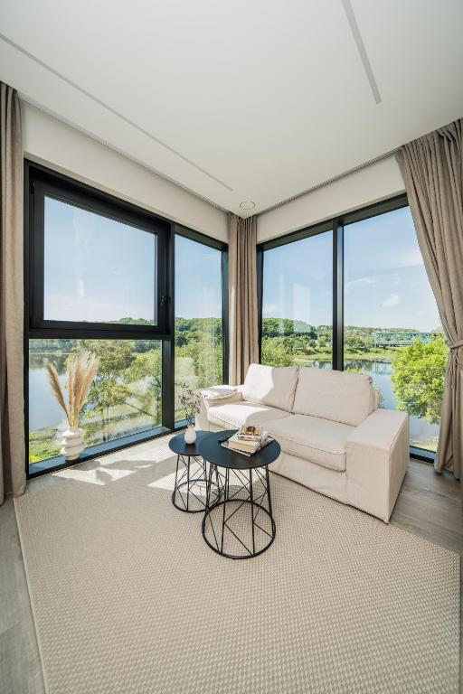 a living room with a white couch and large windows at Kaunorama Riverside Suite, Business & Relax Stay in Kaunas