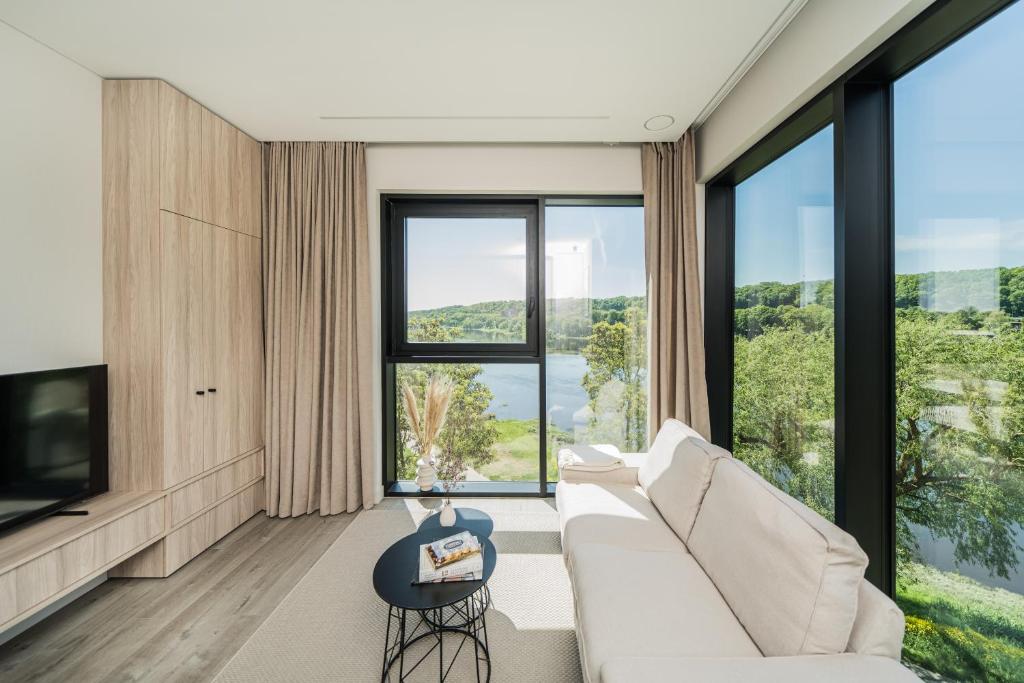 a living room with a white couch and large windows at Kaunorama Riverside Suite in Kaunas