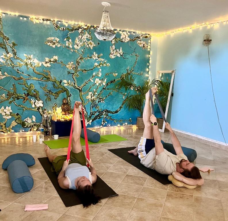 twee vrouwen die yoga doen in een kamer met een boom bij Esmaraldas House of Love in Terrasini