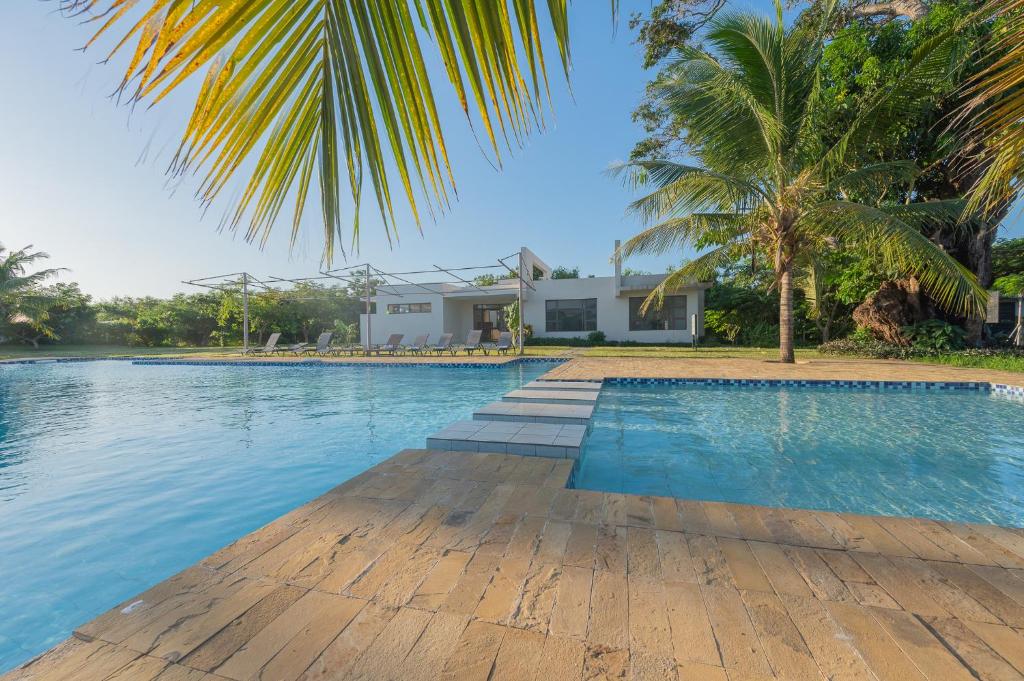 a swimming pool with a palm tree and a house at Kuza The Palm Villas at Vipingo in Kilifi