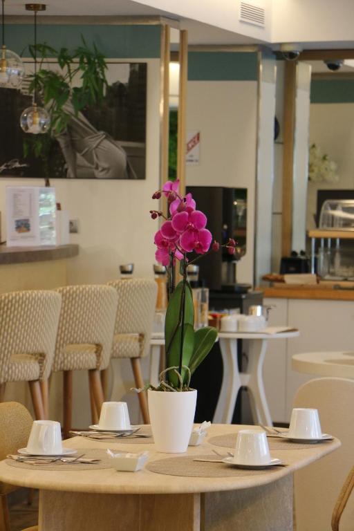 a table with a flower in a pot on it at Hôtel Victoria in Cannes