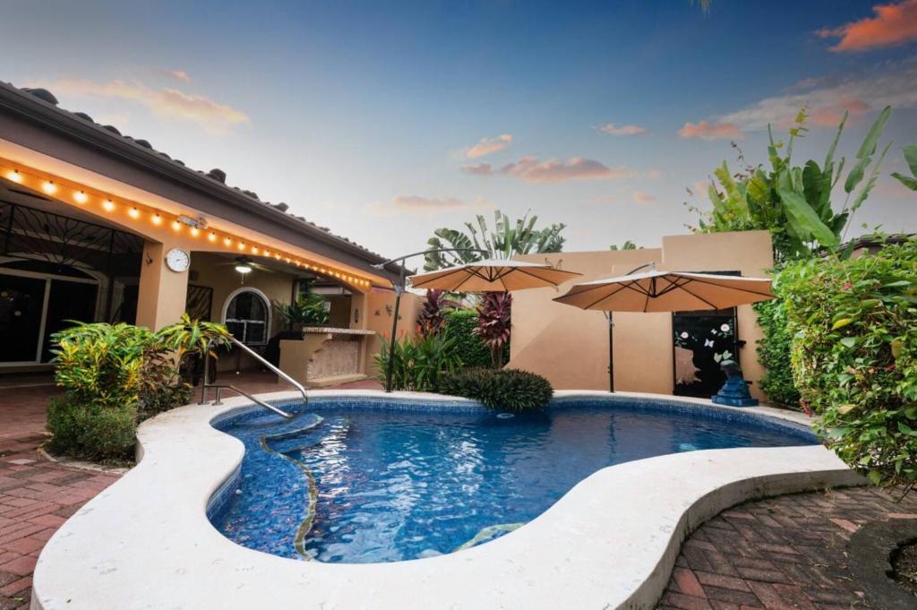 a swimming pool in a yard with umbrellas at Villa Felicidad By Vacation Pura Vida in Esterillos