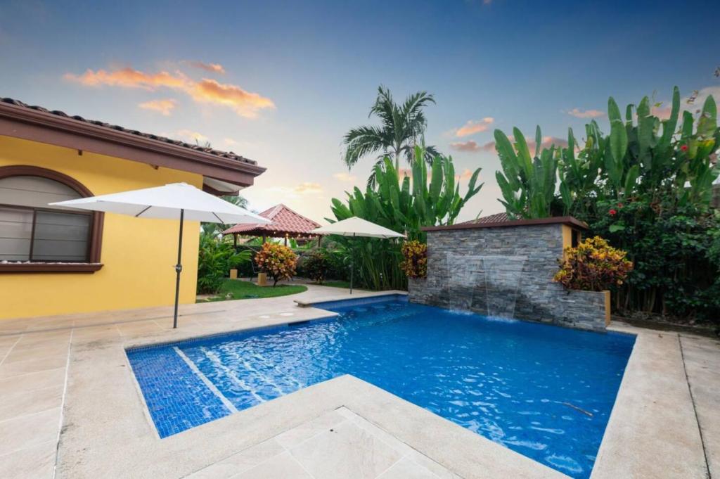 エステリリョスにあるVilla Escapadita By Vacation Pura Vidaの家の隣にある傘付きのスイミングプール