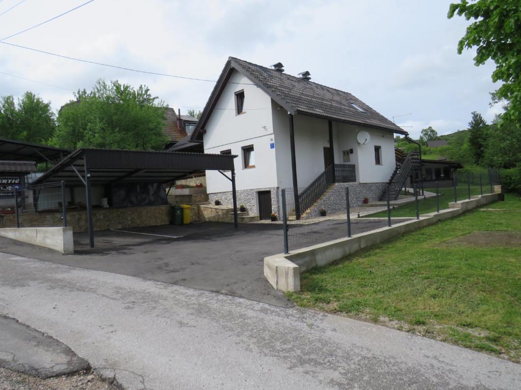 a large white building with a garage and a road at Apartments Sertic 4 stars in Poljanak