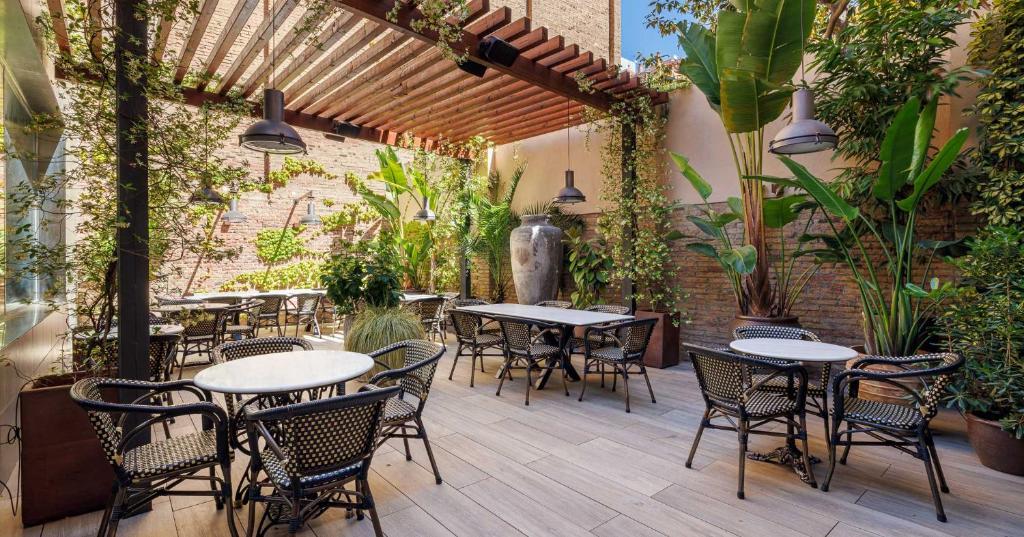 un patio al aire libre con mesas, sillas y plantas en Hotel Ronda Lesseps en Barcelona