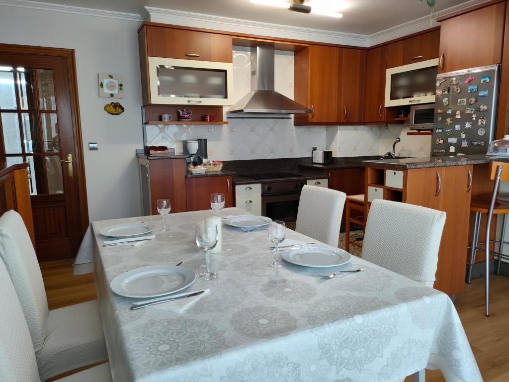 uma cozinha com uma mesa com pratos e copos em Apartamento Xanela o Mar em Laxe