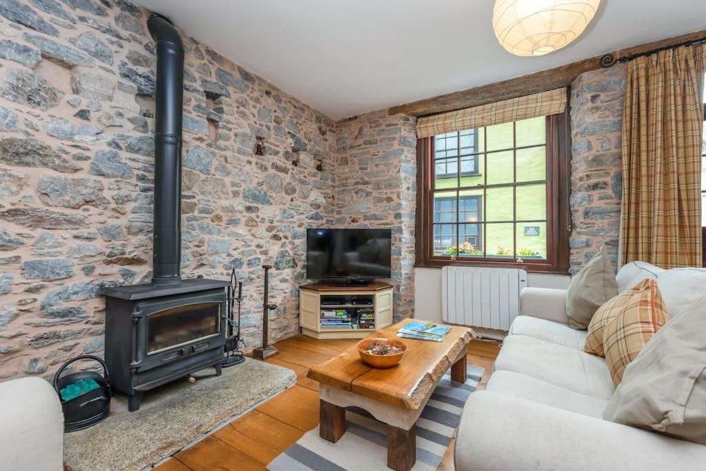 a living room with a brick wall and a stove at River Garden Cottage in Dean