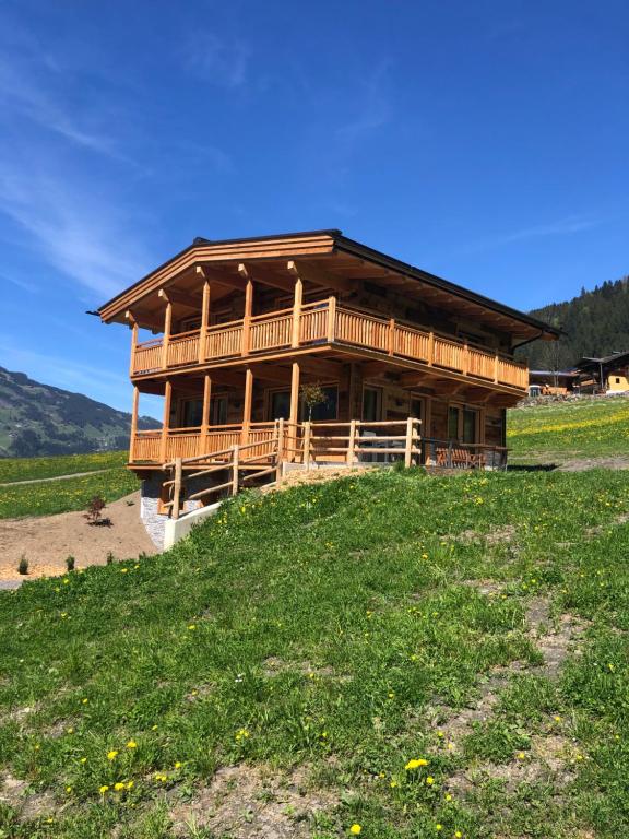uma cabana de madeira no topo de uma colina relvada em Chalet - Das Schrofen em Ramsau im Zillertal