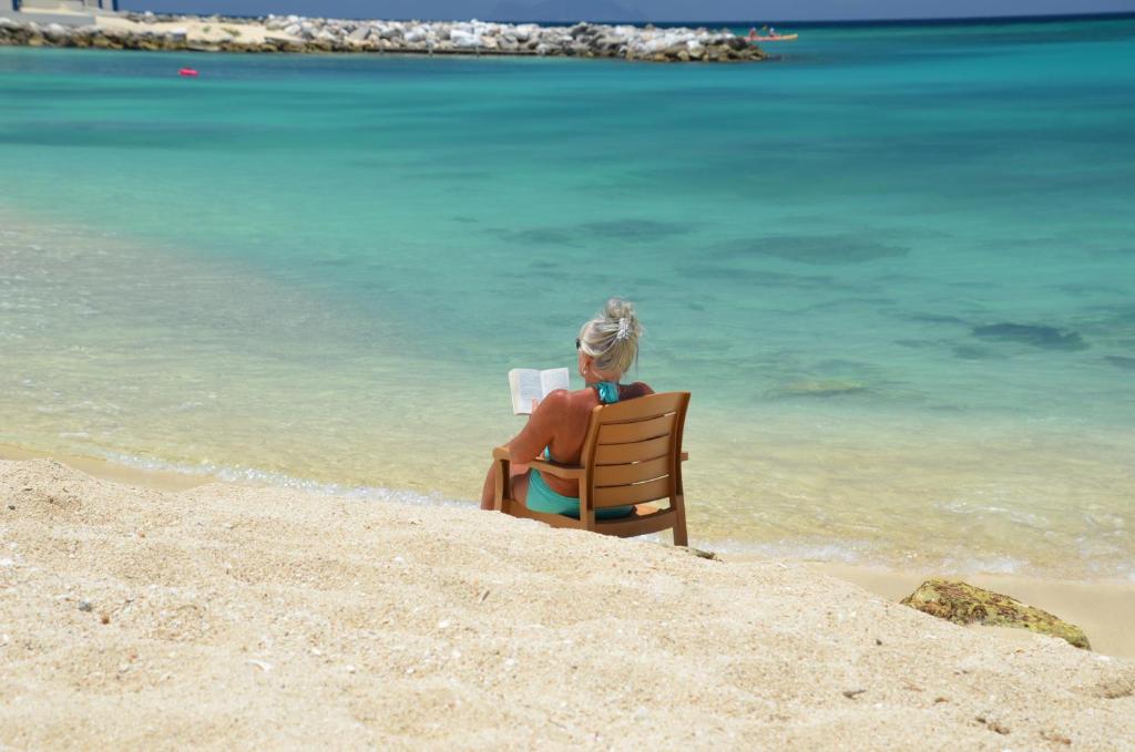 a woman sitting in a chair on the beach at Simpson Bay Resort Marina & Spa in Simpson Bay