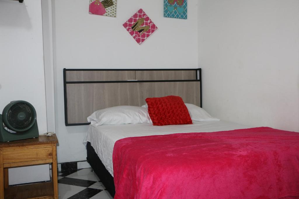 a bedroom with a bed with a red pillow on it at Aparta Suite Torre De Prado 302 in Medellín