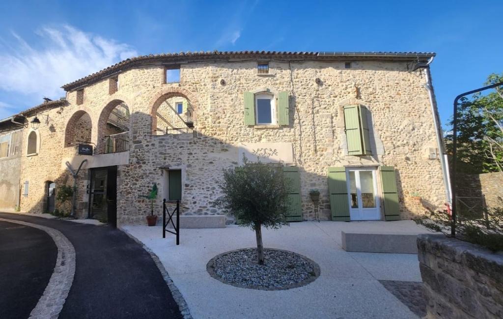 un grand bâtiment en pierre avec un arbre devant dans l'établissement Gîtes NouLou, appartementen in Saint-Denis, à Saint-Denis