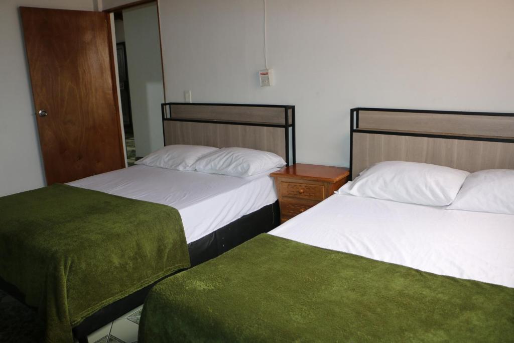 2 camas en una habitación de hotel con sábanas verdes en Aparta Suite Torre De Prado Penthouse, en Medellín