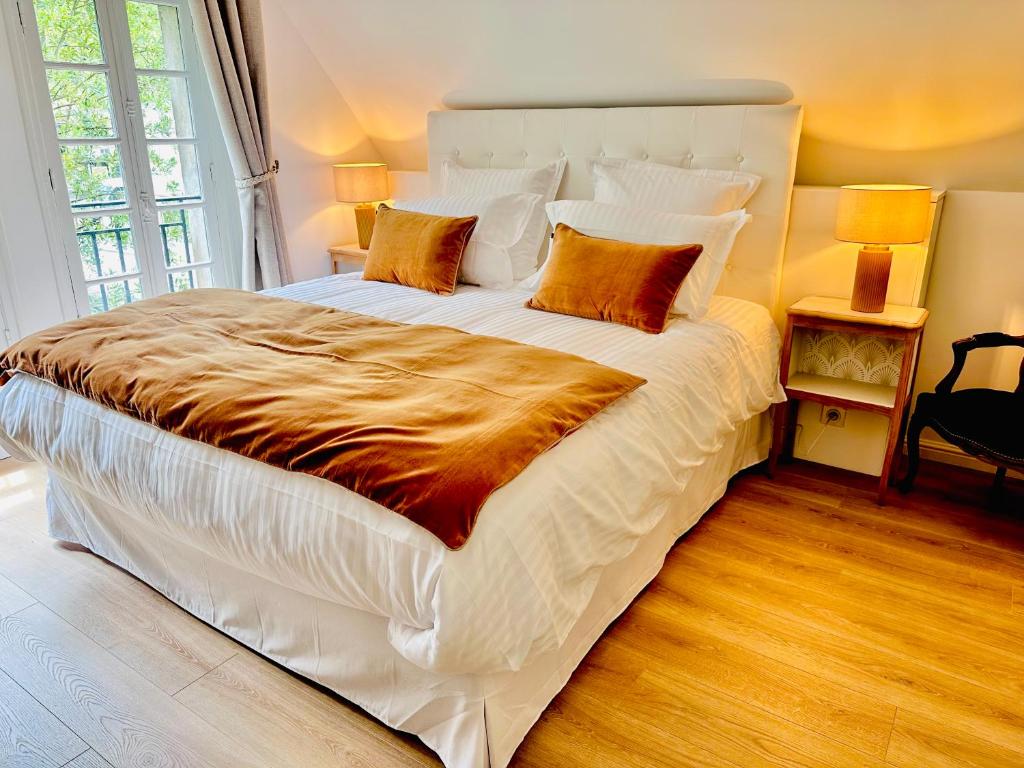 - une chambre dotée d'un grand lit avec des draps blancs et des oreillers orange dans l'établissement Villa Elisabeth, à Versailles