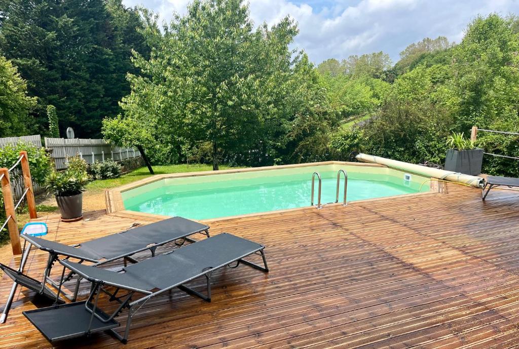 una piscina en una terraza de madera con 2 sillas en SARLAT Centre ville - Appartement avec jardin et piscine en Sarlat-la-Canéda