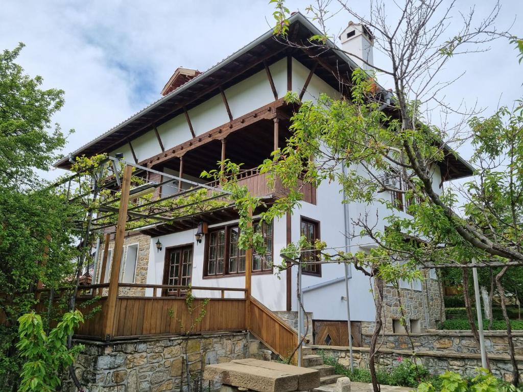 uma casa branca com varanda e árvores em Arbanassi Hotel em Arbanasi