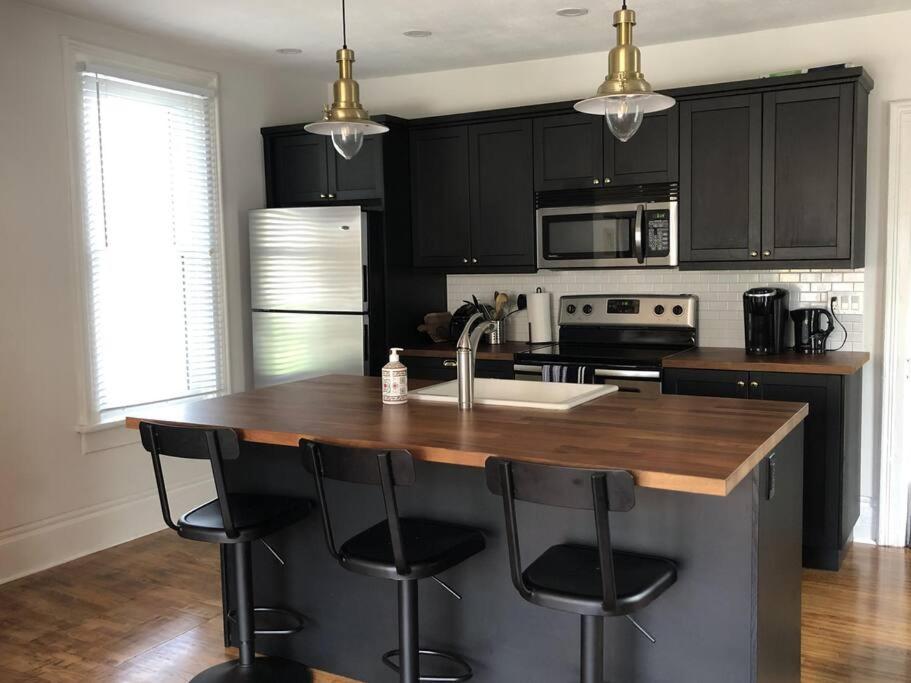 a kitchen with black cabinets and a kitchen island with bar stools at Hill Street Hangout in Picton