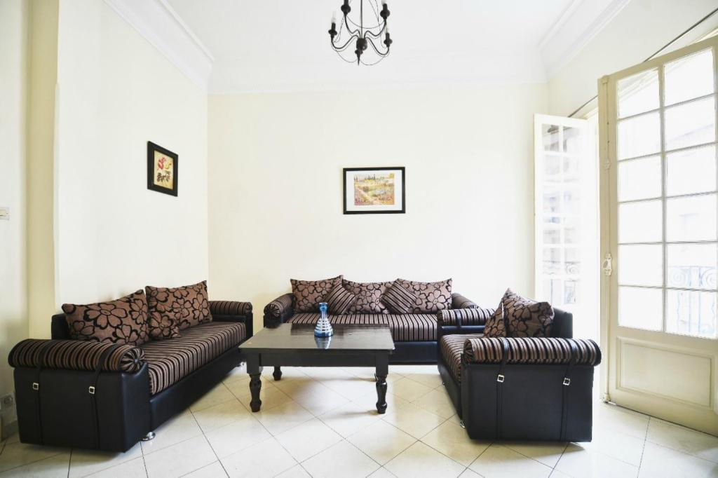 a living room with two couches and a table at Cosy Art Deco Apart Welcome to James's in Casablanca