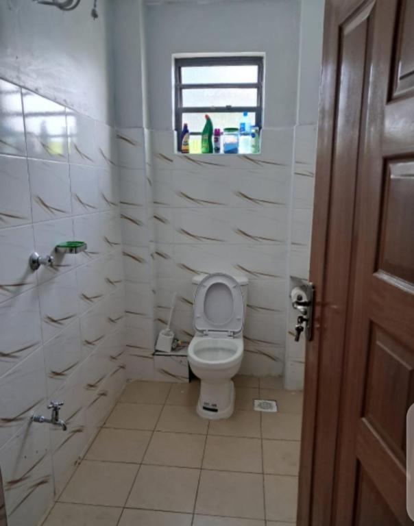 a white bathroom with a toilet and a window at Palm homes in Mutomo