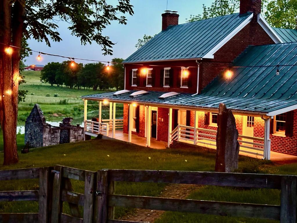 uma casa vermelha com um telhado de metal e uma cerca em Carriage Stone Farm & Horse Ranch em Luray