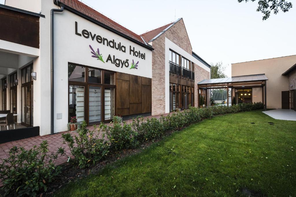 a building with a lawn in front of it at Levendula Hotel in Algyő