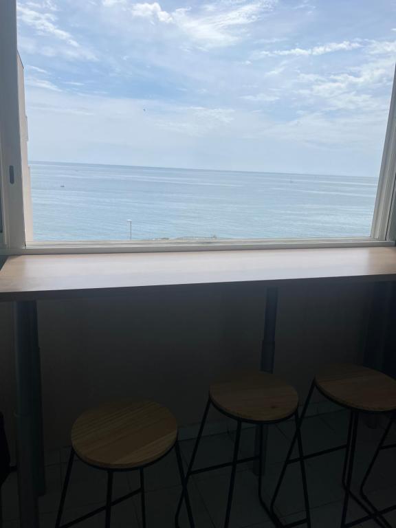 a window with two stools looking out at the ocean at Appartement vue mer in Sète