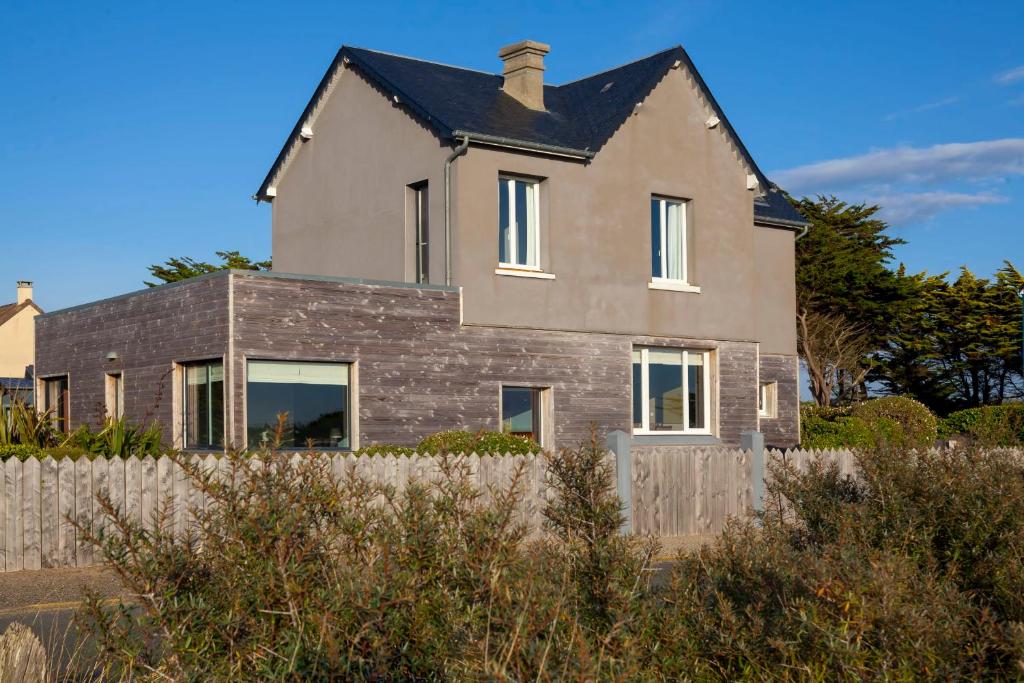 una casa con una valla delante en Beautiful beach house 220m2 Perfectly equipped for 9 people baby, en Barneville-Carteret