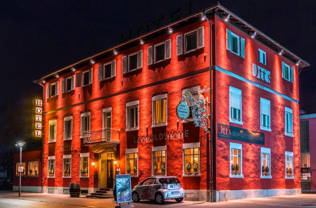ein rotes Gebäude mit einem davor geparkt in der Unterkunft Ott's Hotel Weinwirtschaft & Biergarten Weil am Rhein/Basel in Weil am Rhein