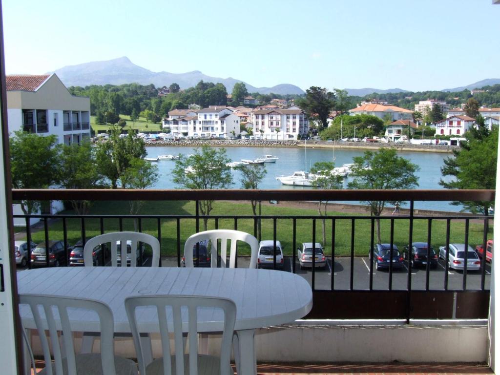 einen Tisch und Stühle auf einem Balkon mit Flussblick in der Unterkunft Appartement dans résidence, plage et centre ville à pied in Saint-Jean-de-Luz