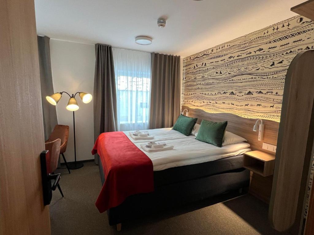 um quarto de hotel com uma cama com um cobertor vermelho em Arctic Hotel Nordkapp em Honningsvåg