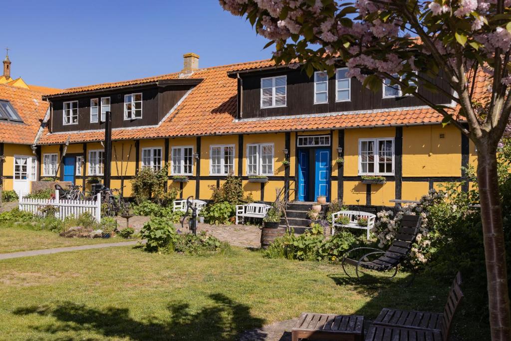 una casa amarilla con una puerta azul y un patio en Pension Slægtsgaarden en Allinge