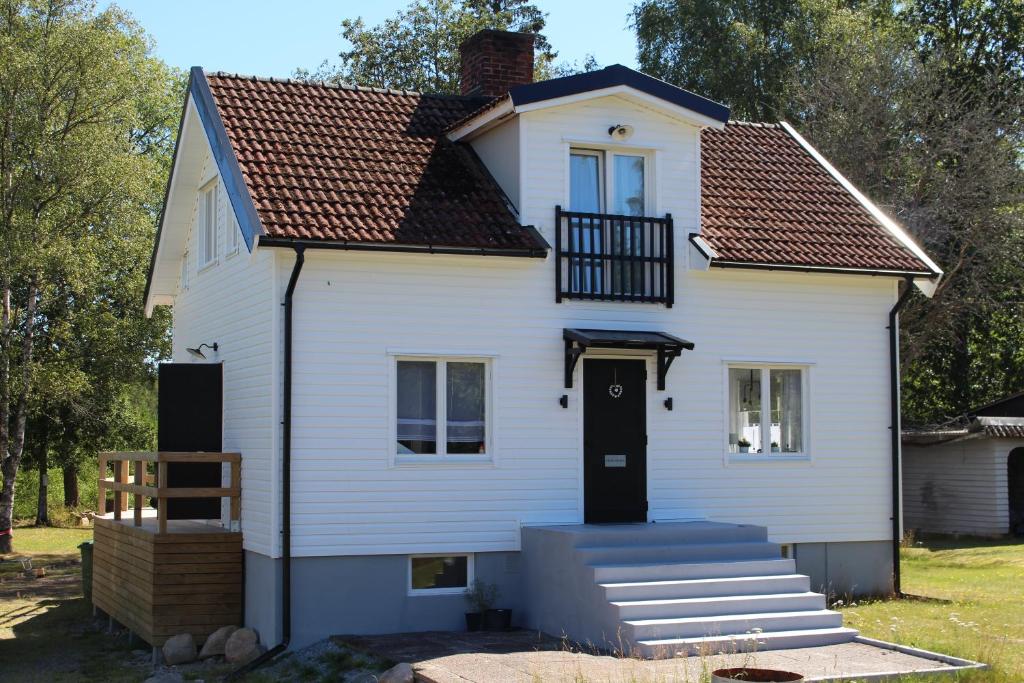 a white house with a black door and stairs at Schönes schwedisches Cottage in Seenähe mitten im Glasreich in Målerås