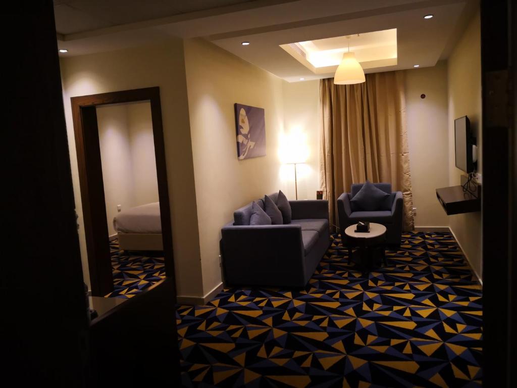 Ocean View Al Zahra في جدة: غرفة معيشة مع أريكة وكراسي في غرفة في الفندق