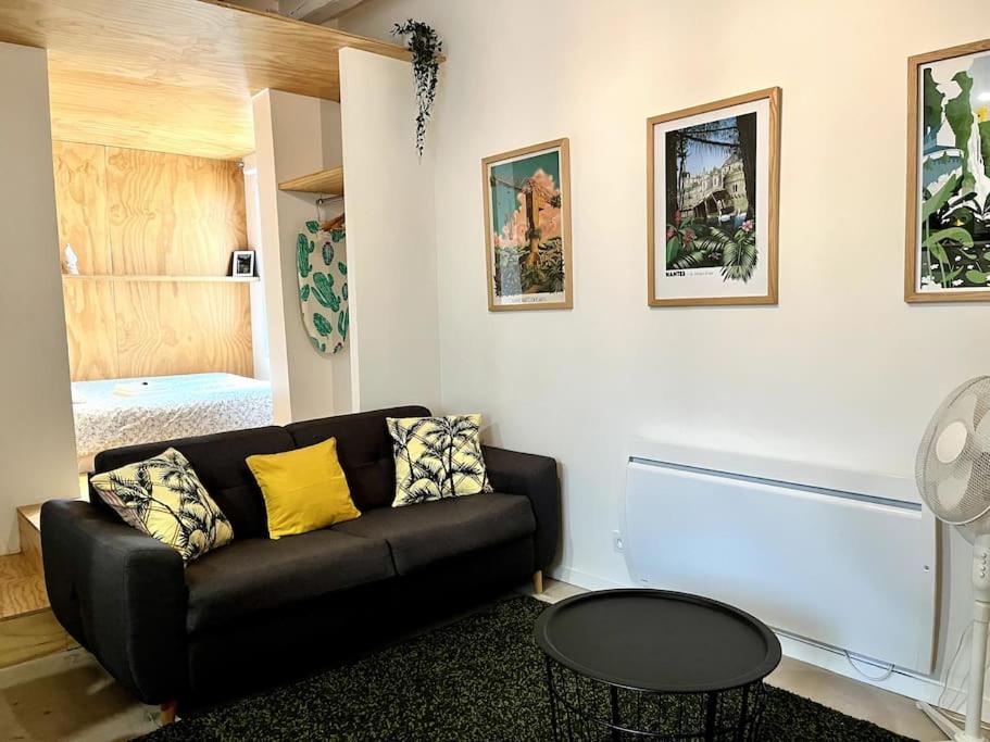 un salon avec un canapé noir et une table dans l'établissement Le Madeleine, 2pers wifi et Tv, à Nantes