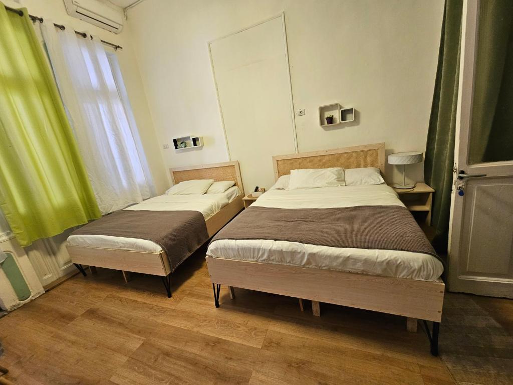 2 camas en una habitación con cortinas verdes en City Hostel Dormitory, en Trípoli