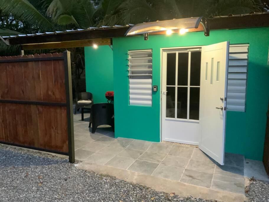 a green house with a white door and a fence at Hospederia Villa Alegre Estudio 7 in Cabo Rojo