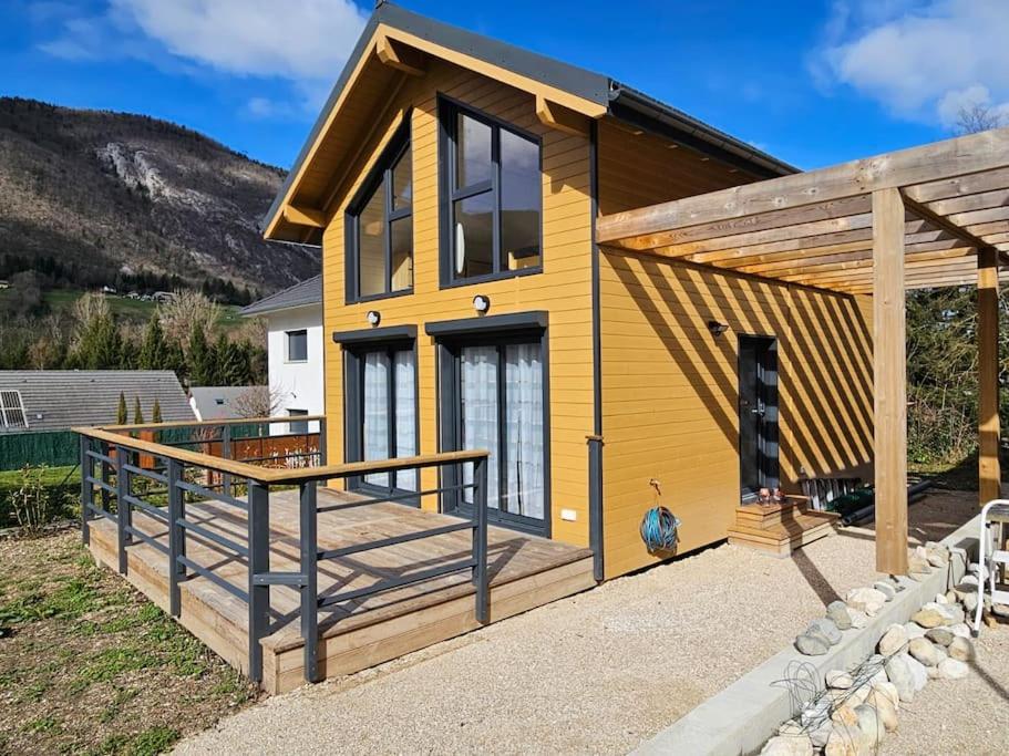 a house with a large deck in front of it at Maison bois de 65m² in Saint-Thibaud-de-Couz